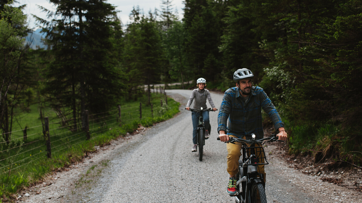 Ein Mann und eine Frau fahren mit einem E-Fully, black und matt, in den Bergen